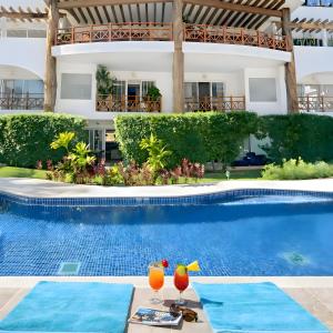 ein Schwimmbad mit zwei Getränken neben einem Gebäude in der Unterkunft Luxury Duplex 2BR Pool & Garden View Quiet 30m from 5th Ave with Gym & Parking in Playa del Carmen