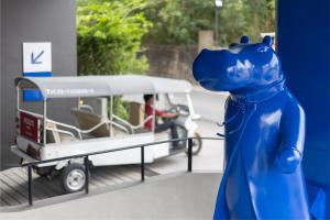 a blue dog standing in front of a bus at Blue Hippo & Red Crocodile Hotel in Bangna