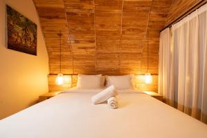 a bedroom with a white bed with a wooden wall at Omaneil Villa in Uluwatu