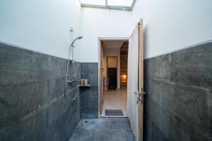 a bathroom with a shower with a door open at Omaneil Villa in Uluwatu +11 photos