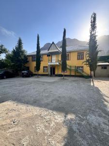 a yellow building with two trees in front of it at Sharshara-Darvoz in Sangovy