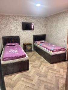 two beds in a room with a tv on the wall at Sharshara-Darvoz in Sangovy +11 photos