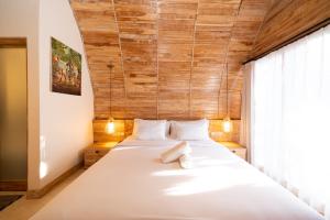 a bedroom with a large white bed with a wooden wall at Omaneil Villa in Uluwatu