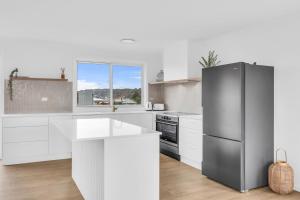 a kitchen with a stainless steel refrigerator and white cabinets at Callow Place 10 in Bermagui