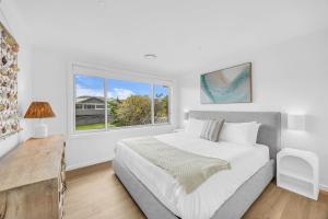 a white bedroom with a large bed and a window at Callow Place 10 in Bermagui