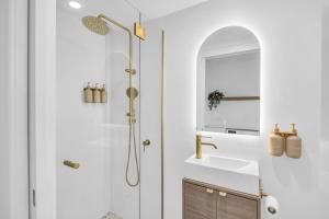 a bathroom with a shower and a sink and a mirror at Callow Place 10 in Bermagui +18 photos