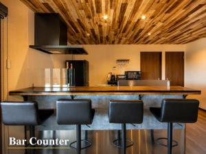 a kitchen with a bar counter with black stools at 千葉地域ランキング1位獲得の贅沢な貸別荘全4棟 in Hota