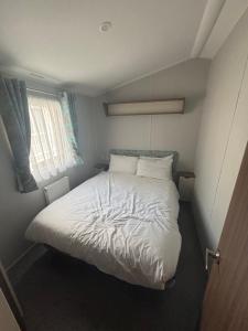 a small bedroom with a white bed and a window at Explorer45 in Lytchett Minster