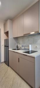 a kitchen with white cabinets and a sink and a refrigerator at Sea&Sunset Studio in Sozopol