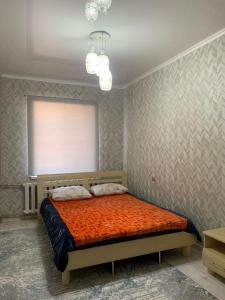 a bedroom with a bed with an orange comforter at Толе би 141А in Qyzylorda