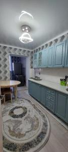 a kitchen with blue cabinets and a table and a rug at Толе би 141А in Qyzylorda