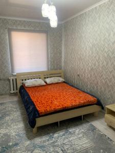 a bedroom with a bed with an orange comforter at Толе би 141А in Qyzylorda +6 photos