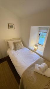 a bedroom with a white bed and a window at Sunnyside Cottage in Sedbergh
