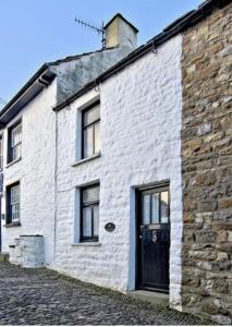 a white brick building with a black door at Sunnyside Cottage in Sedbergh