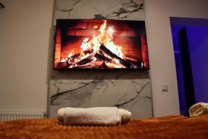 a fire in a fireplace with a tv on a wall at Om relax apartman in Prijedor