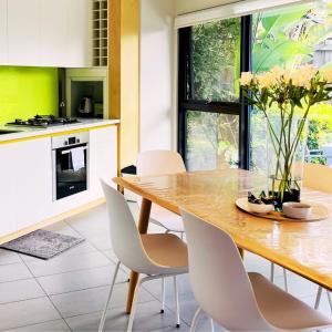 a kitchen with a wooden table and white chairs at Fusion Townhouse-North Hobart in West Hobart