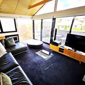 a living room with a couch and a flat screen tv at Fusion Townhouse-North Hobart in West Hobart