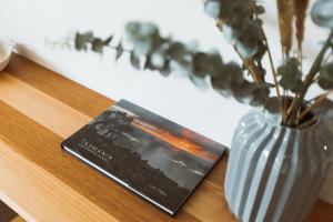a book sitting on a table next to a vase at Montage Apartment + Views + Location + Car Parking in Bellerive