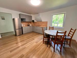 a kitchen with a table and chairs and a refrigerator at Pakalnės sodyba in Skverbai