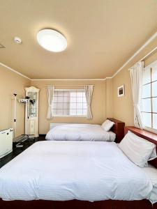 two beds in a room with two windows at 北海道大学ENYA-n17 in Sapporo