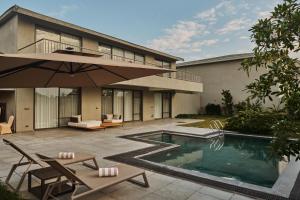 a house with a swimming pool and an umbrella at Arth Resorts I Convention I Wellness in Moinabad