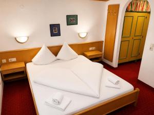 a bedroom with a bed with white sheets and pillows at Schönmoosalm in Krimml