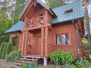 a wooden cabin with a porch and a balcony at Przystanek Jezioro - Kaszuby in Studzienice