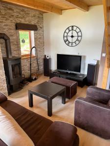 a living room with a couch and a clock on the wall at Przystanek Jezioro - Kaszuby in Studzienice +9 photos