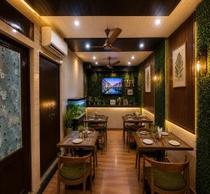a restaurant with wooden tables and chairs and a tv at Hotel La Casa Near Delhi Airport in New Delhi