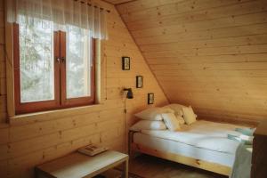 a small room with a bed in a log cabin at Jarzębinowa - artystyczny dom na Podlasiu in Łuka