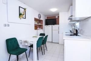 a kitchen with a white table and green chairs at Villa Bazilika in Sečovlje