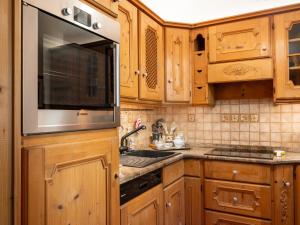 a kitchen with wooden cabinets and a microwave at Villa Marmarole - Croda Bianca Apartment in Calalzo
