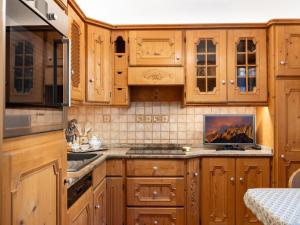a kitchen with wooden cabinets and a sink at Villa Marmarole - Croda Bianca Apartment in Calalzo