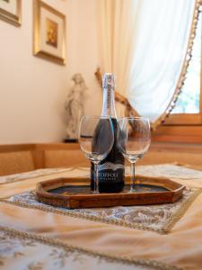 a bottle of wine and two wine glasses on a tray at Villa Marmarole - Croda Bianca Apartment in Calalzo +56 photos