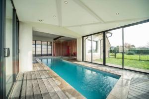 a swimming pool in a house with windows at Les Grandes Vagastines in Saint-Germain-du-Plain