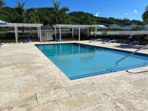 a swimming pool with chairs and a gazebo at Oceanpointe Serenity Get Away-solar pool WiFi in Lucea