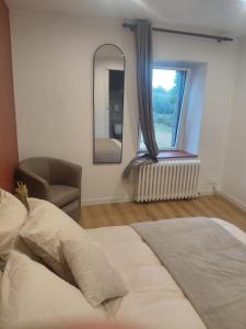 a bedroom with a bed and a chair and a window at Chambre in Ploumilliau