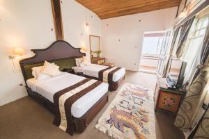 two beds in a room with a dragon on the wall at Netuk House a heritage boutique stay in Gangtok