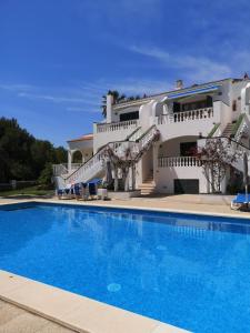 a villa with a swimming pool in front of a house at Nice apartment with a pool in Fornells