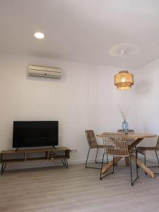 a living room with a television and a table and chairs at Nice apartment with a pool in Fornells
