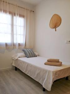 a bed in a white room with a window at Nice apartment with a pool in Fornells +3 photos