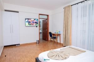 a bedroom with a bed and a table with a chair at The Dalton Grand Hotel in Murangʼa
