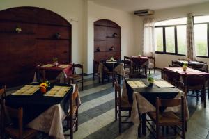 a dining room with tables and chairs and windows at Posada di Portixeddu in Portixeddu