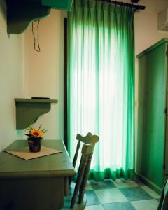 a kitchen with a table and a green curtain at Posada di Portixeddu in Portixeddu