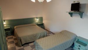 a bedroom with two beds and a tv on the wall at Posada di Portixeddu in Portixeddu