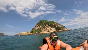 a person in a life vest in the water with an island at Hostal Fragata Puerto López in Puerto López