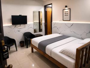 a bedroom with a bed and a flat screen tv at Wayan Luxury Rooms in Hyderabad