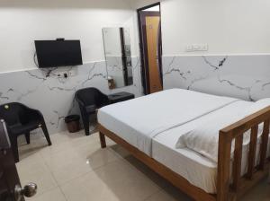 a bedroom with a bed and a tv and chairs at Wayan Luxury Rooms in Hyderabad