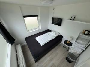 a small bedroom with a black bed and a window at Slottets Anneks in Rønne