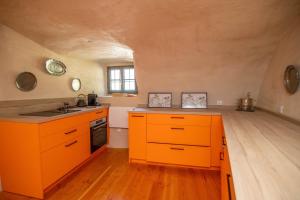 an orange kitchen with a sink and a stove at Les Petits Princes, expérience unique à Polignac in Polignac +29 photos
